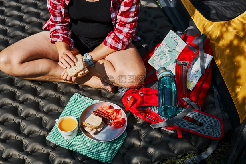 在露营地帐篷旁坐着早餐的妇女积极在靠近自然户外的地方过暑假难民营生活概念女积极度暑假徒步旅行漫娱乐图片