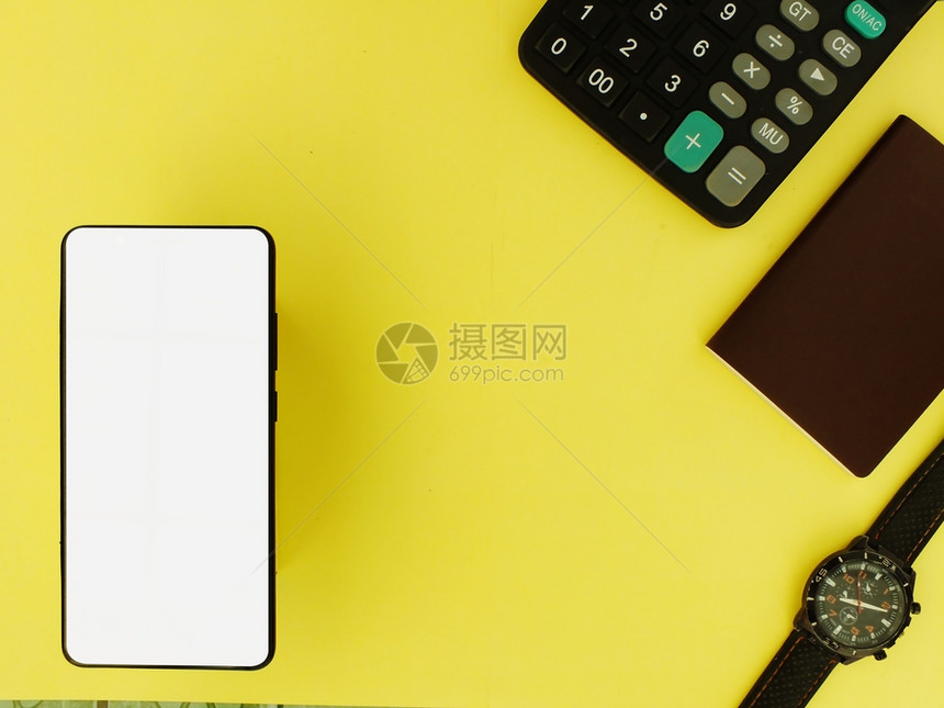 白屏幕智能手机配有计算器和黄色背景旁观银行业经济的木制图片