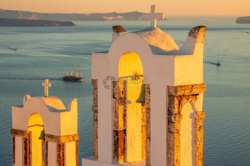 地中海天空一种希腊在奥亚和港景希腊礼拜堂ThiraBells岛的希腊日落与一艘教堂和Thira湾观的帆船钟图片