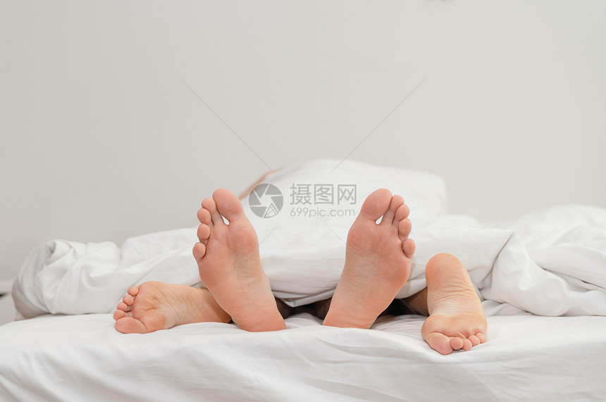 亲密重点在白毯子下的情侣脚足在床上浪漫的图片