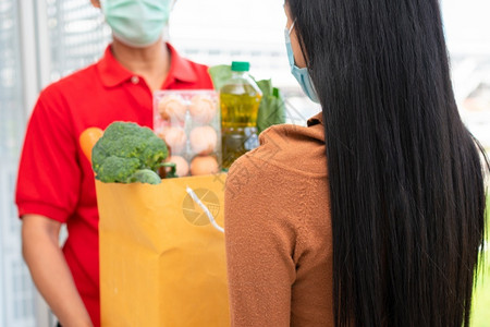 包面具来自超市的亚洲送货员身戴面罩持有一袋新鲜食品蔬菜和水果供家里顾客使用特快杂货服务和新生活方式概念服务与新生活方式白种人交货高清图片素材