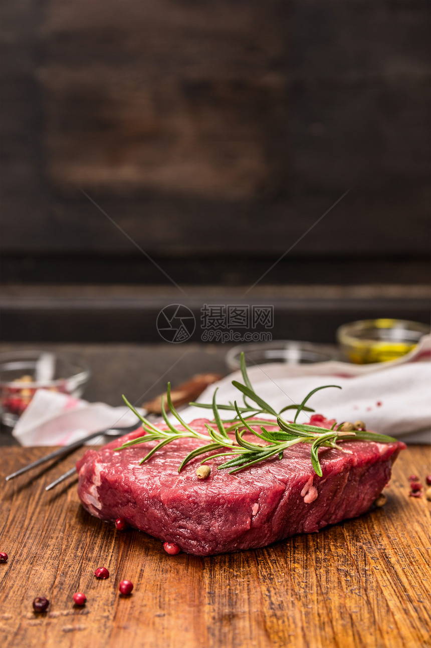 乡村新鲜的炖生牛肉排配有在黑织背景的生锈风衣桌上烹饪的原料图片