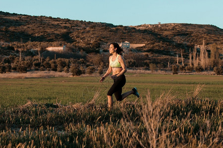 女士跑步者在春草林中自然界的锻炼运动日出训练图片