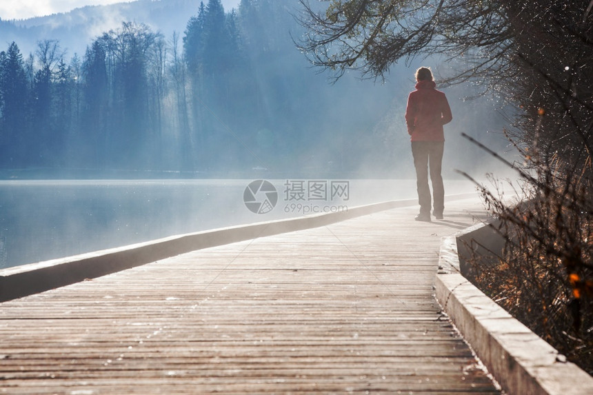 淑女多雾路段美丽秋天在雾日出时独自一人湖边的女子图片