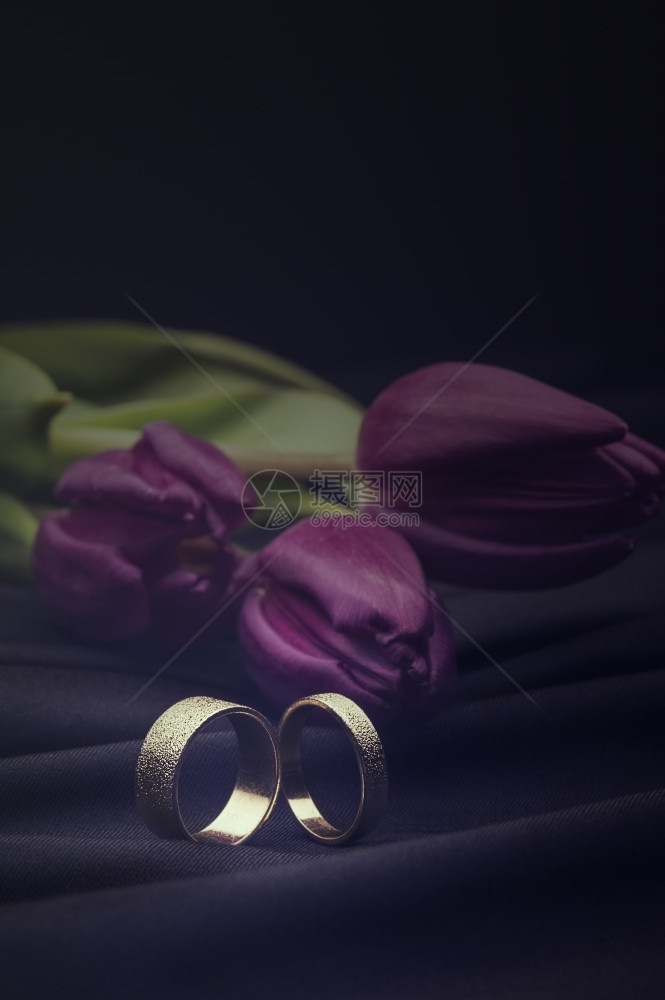 白金结婚戒指带有花束罗马式白金结婚戒指挂在软豪华黑布上盛着一束鲜紫春郁金花束上面有复制版问候婚礼配件图片