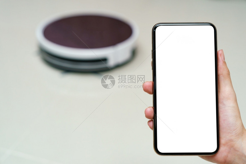 家政消隐管理手持带空白屏的智能手机以控制器人真空清洁吸尘器智能生命技术概念图片