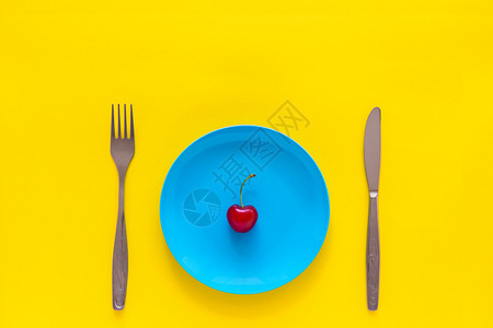 樱桃蓝色营养甜的重量蓝盘刀叉子黄底顶视平面复制空间概念夏季和饮食体重减肥的单一成熟樱桃背景
