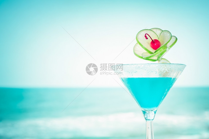 龙舌兰酒蓝色玛格丽塔鸡尾酒在热带海洋滩的滨上配有石灰水果和樱桃装饰品的蓝色玛格丽塔鸡尾酒柠檬派对图片