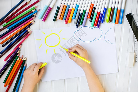 女孩自我表达童子手用彩色铅笔涂在木制桌上一张白纸童子手用彩色铅笔画在纸上屋婴儿高清图片素材
