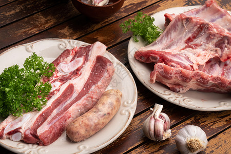 新鲜的猪排牛肉和木桌上的香肠准备在西班牙楚拉斯科烧烤时煮熟营养劈生的图片