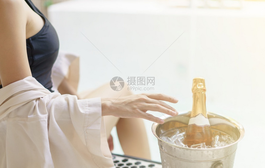 采取年轻的在泡池附近黑泳衣喝着葡萄酒的女子之手海图片