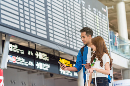 旅游飞机朋友们亚洲夫妇旅行者使用智能移动电话在机场现代飞行信息屏幕上登机旅行和带有技术概念的交通方面使用智能移动电话进行亚洲夫妇曼谷高清图片素材