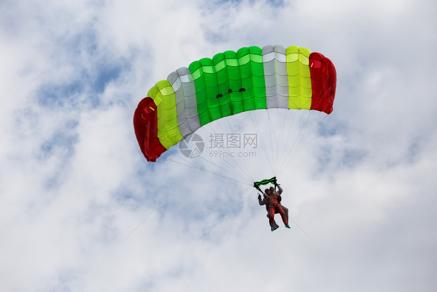 在多云的天空中乘坐彩色降落伞下的串联兵乘坐彩色降落伞的下串联兵闲暇危险的爱好图片