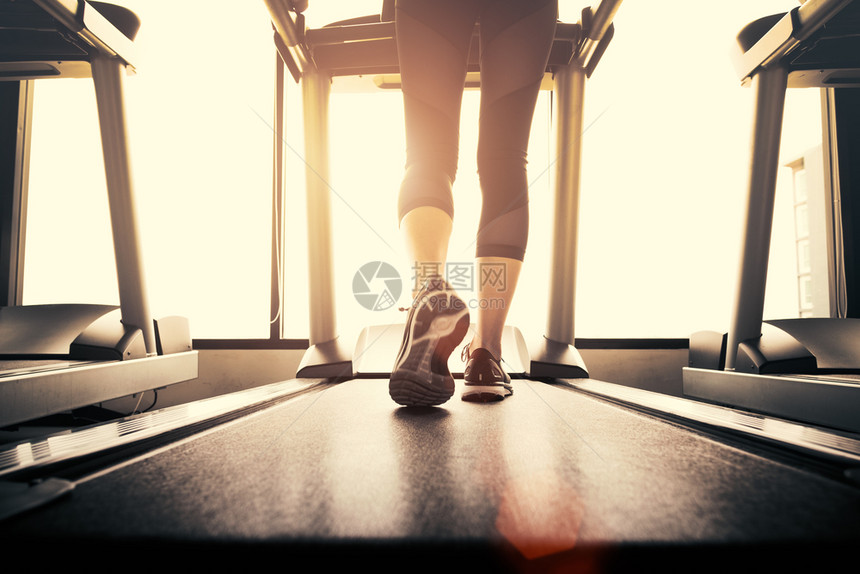 美丽的吸引人或者健康与锻炼活动概念健身和强力训练主题在健身房运行机或动场上跑步的健身女孩腿下部体用阳光照射温暖的语调图片