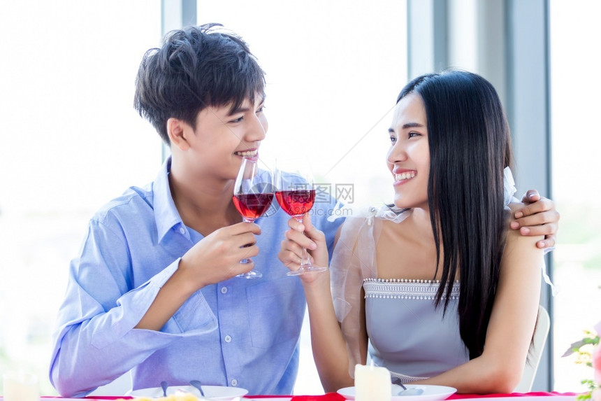 华伦多人节日概念快乐的亚洲年轻甜蜜情侣在餐厅背景上浪漫的午餐和熟连着烤红酒杯团结玻璃庆祝图片