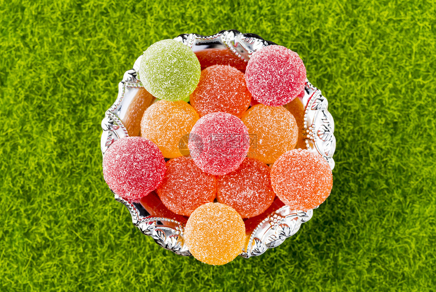 胶桩彩色果冻罐头在绿草背景的风上青草背有色水果冻罐头糖图片