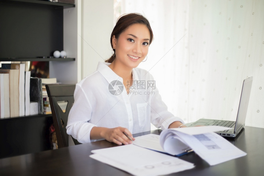 美丽的亚洲女商人检查文件使用笔记本并快乐地笑着工作的微职业办公室金融图片