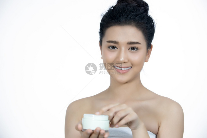 一位使用皮肤护理产品润湿剂或滑的美丽女亚洲人在手中照料她的干乳油奶模型肖像脸图片