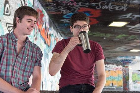年轻的城市格拉菲提斯滑板公园两间不时青年成人饮用咖啡与聊天城市的背景图片