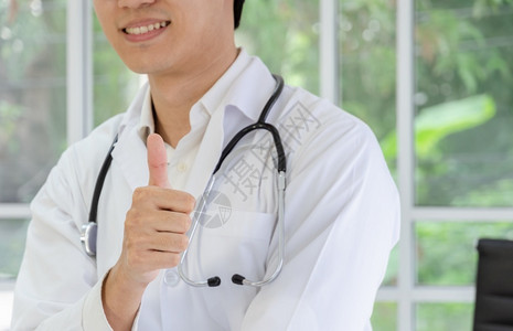 穿着白大衣的微笑男医生露出拇指手举起标志保健与险概念积极的快乐医师高清图片素材