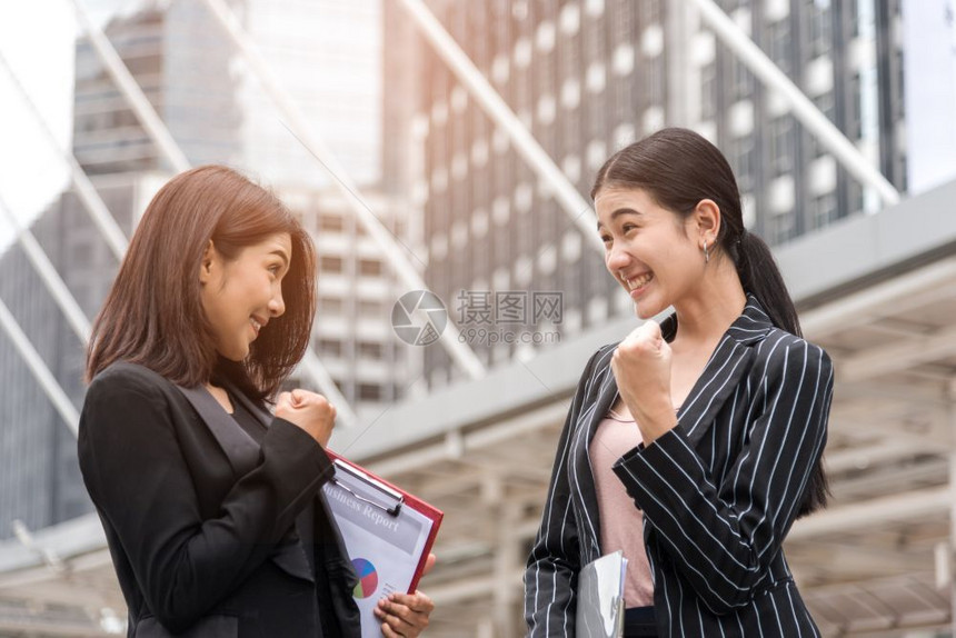 漂亮的黑色女两名商界妇在户外快乐地举手企业成就和功的概念商业图片