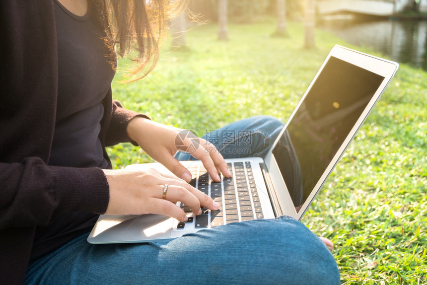 青年在户外坐在草地上使用笔记本电脑图片