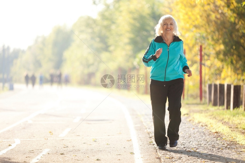 追踪70岁的老年妇女在明秋晚的Pedestrian漫步道上慢跑蓝色的户外图片