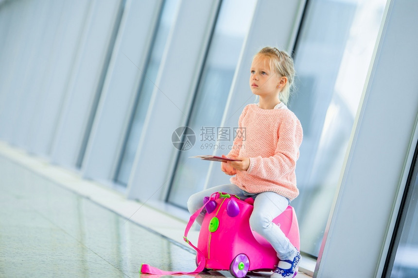 包航班飞机在大国际场的适客小女孩靠近窗户边的适客小女孩机场的适客小女孩她的行李在等待登机图片
