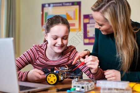 大学导师老的女教帮助孩建造机器人车科学课程中的女教师图片