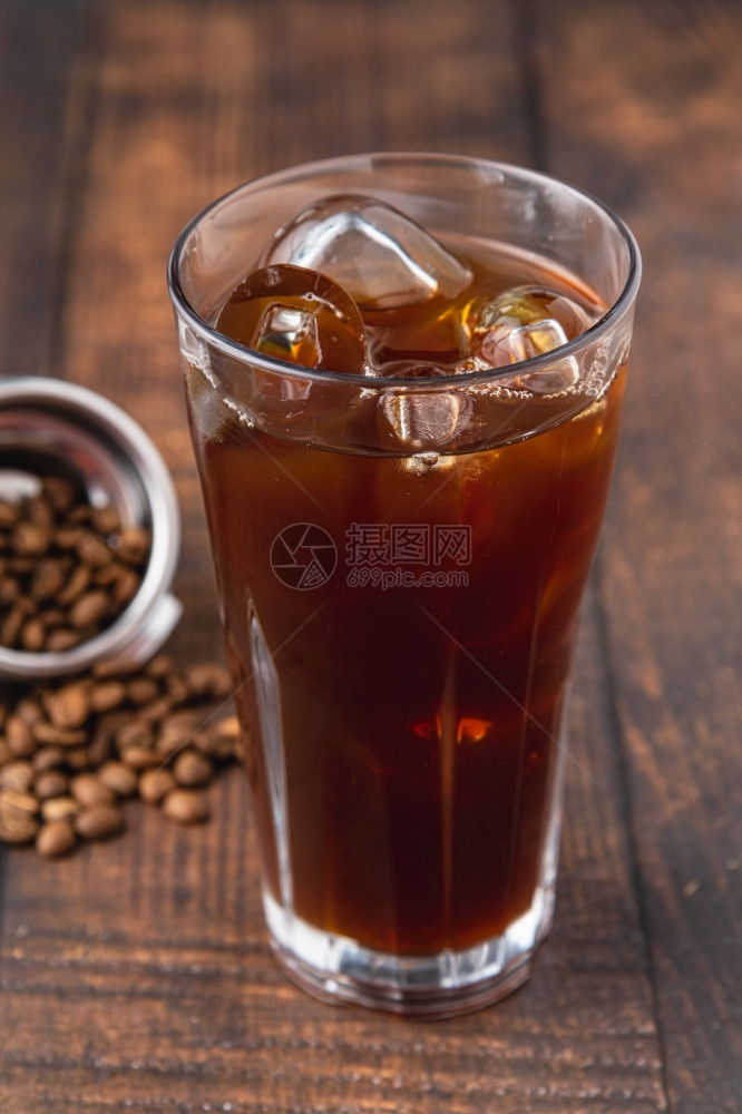 杯子黑暗的棕色一杯冰美式咖啡块放在店的木桌上图片