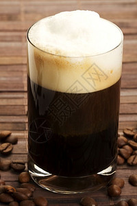 黑色的豆子浓咖啡加奶泡和豆浓加奶泡和豆在木质背景上发泡的图片