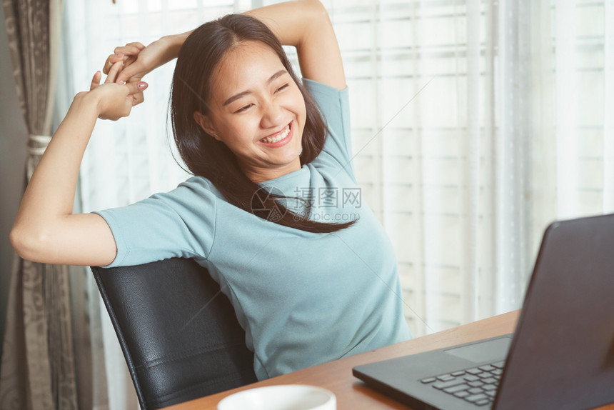 成功年轻的漂亮长时间在笔记本电脑上工作的亚洲女孩妇厌倦了工作伸展放松和笑容图片