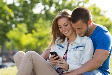 金发女郎夫妻在手机中的信件上结对年轻的情侣图片