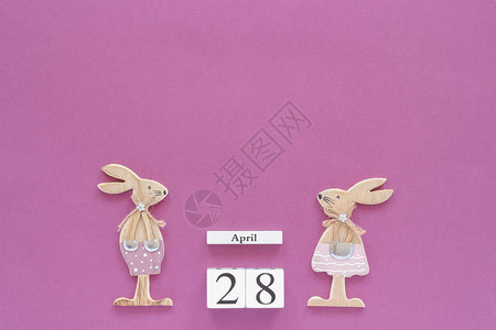 帕施平坦的木制立方体日历4月28日和一对木制复活节兔子在紫色纸背景上用于刻字文本或您的设计创意顶视图的空间模板庆典背景图片