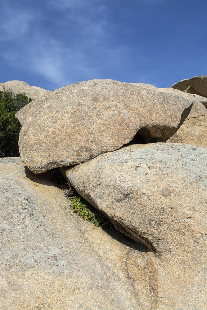 岩石位于被侵蚀悬崖顶上的花岗岩板在意大利萨丁亚州斯梅拉尔达的CostaSmeralda有蓝天模糊云雾在被侵蚀悬崖顶面的意大利撒丁图片