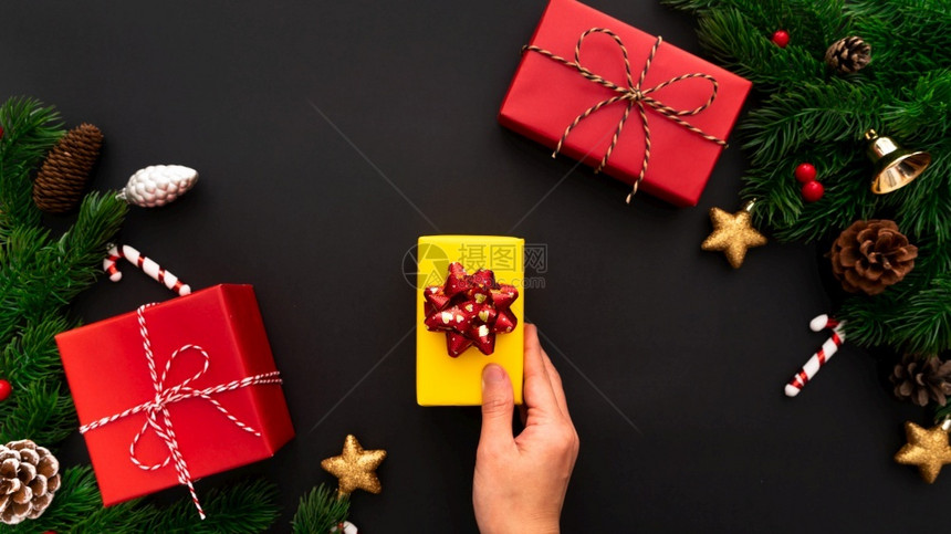 白色的十二月展示手握圣诞礼物盒和松树黑色背景有X马装饰品图片