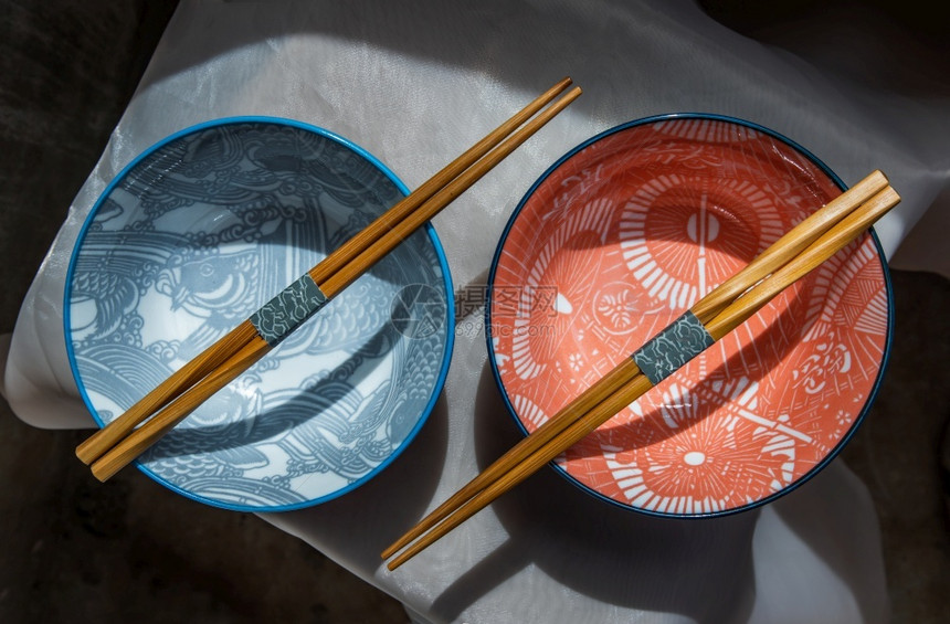 两个陶瓷碗粉桌布上有木筷子的陶瓷餐具美丽安排顶视图选择焦点目的优雅陶瓷制品图片