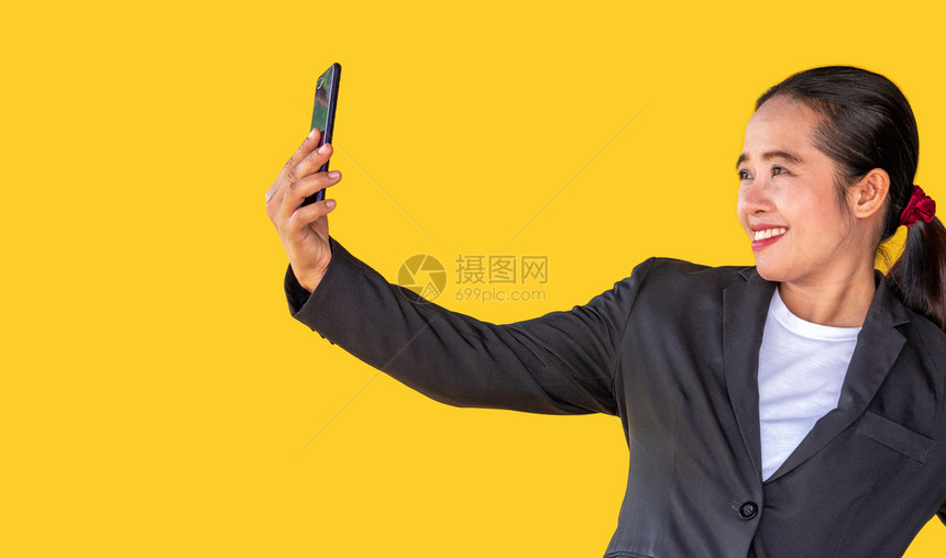 在线的商业妇女使用智能手机在黄色背景下打视频电话人们商界女图片