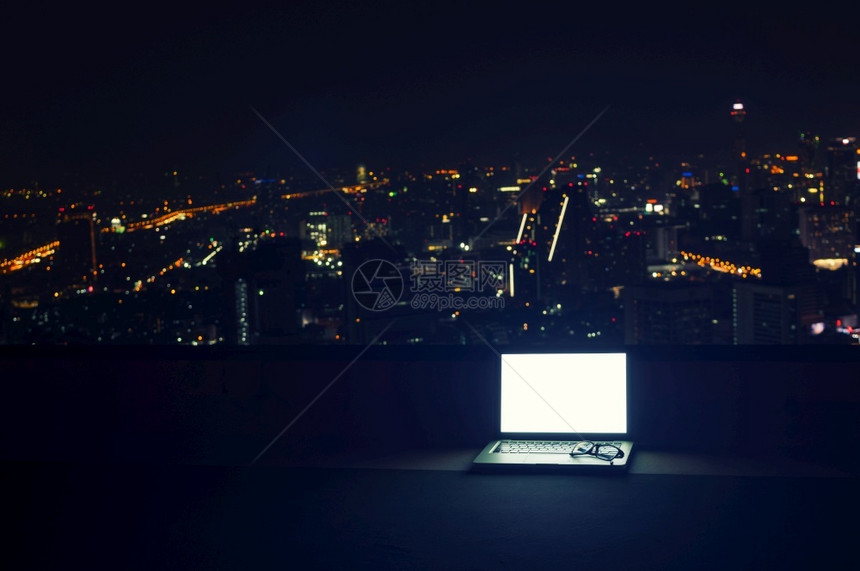 办公室白色的戴在膝上型计算机空白屏幕上的眼镜夜间有城市风景工作间中断概念歇互联网图片