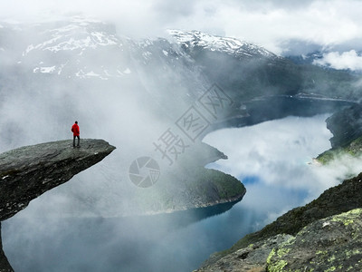 人类坐在山前的Trolltunga尽头奢华故事斯堪的纳维亚图片