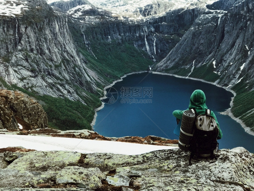 多雾路段人类坐在山前的Trolltunga尽头奢华美丽的图片