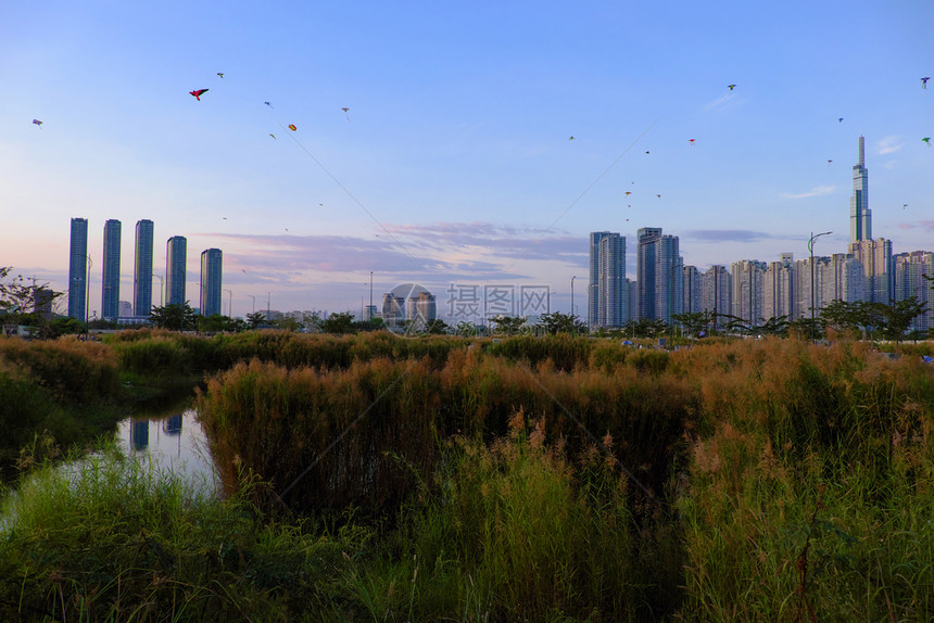 芦苇赛建造越南胡志明市令人惊异的景色晚上越南胡志明市地貌奇异许多风筝在日落天空上飞翔高楼建筑对河流水的反射图片