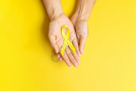 手拿黄丝带预防儿童疾病概念图片