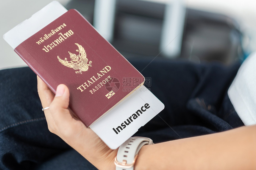 航空公司游客持有泰国护照和旅行保险文件及李袋背景的泰国妇女手持护照和旅行保险证件度假和运输概念旅行和运输文档图片