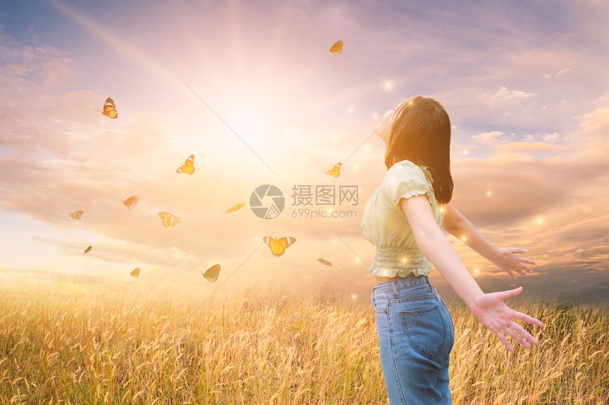 自由与健康一个女孩在太阳下伸展她的手臂在蝴蝶之间快乐的橙幸福图片