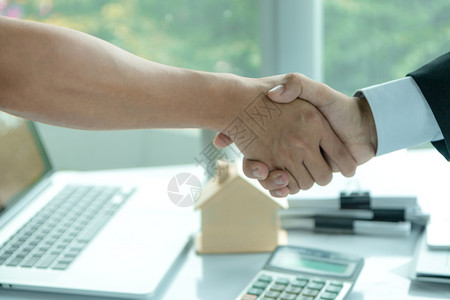 白色的在签署购房合同后产代理商在办公桌上与客户握手和顾专业的买方图片
