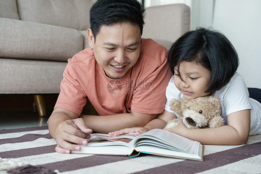 屋快乐的童年亚洲父亲和女儿在家中的地板上阅读书籍自学概念亚洲父女图片