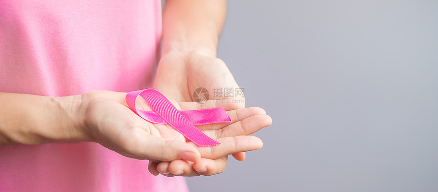 穿粉红T恤的妇女手握粉丝带图片