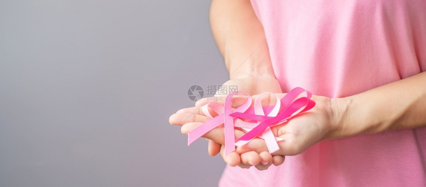 穿粉红T恤的妇女手握粉丝带预防癌症图片