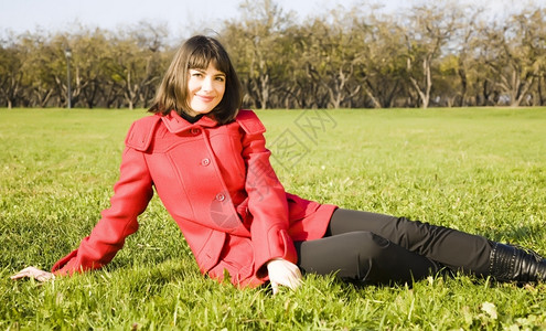 坐在绿草上的年轻女微笑孩外套年轻的高清图片素材